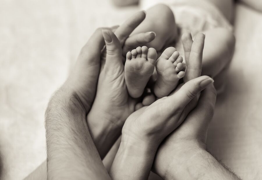 Vater und Mutter umschließen Babyfüsse - die Familie als Urzelle für Weltfrieden