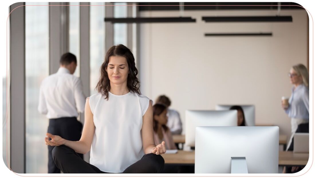 Frau sitzt im Meditationssitz auf Schreibtisch und entspannt während der Menstruation.